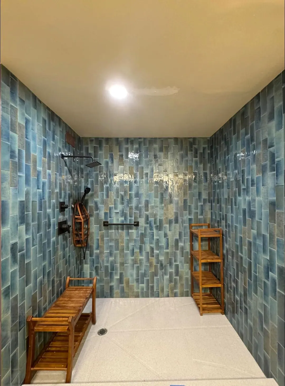 After: Open walk-in shower in blue glazed tile with a teak bench