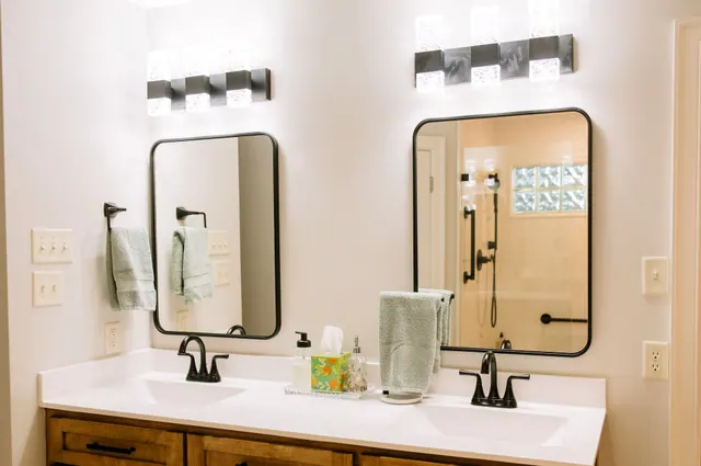 Double vanity in stained wood with black-framed mirrors and bar lights
