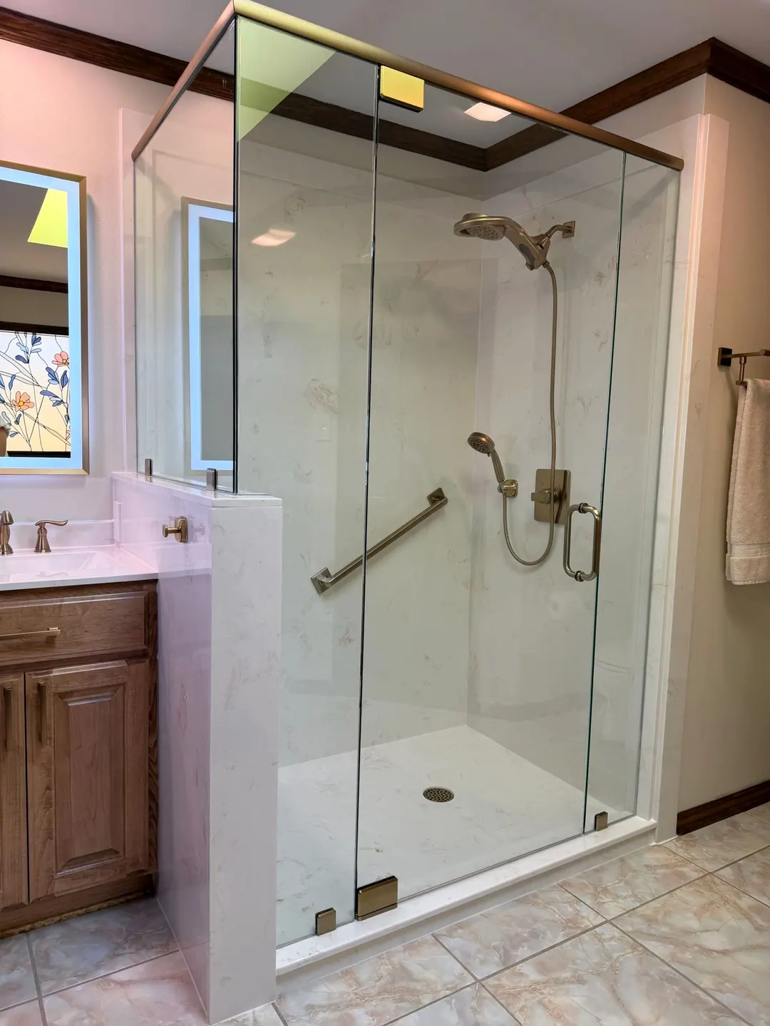 Frameless glass shower with brushed brass fixtures and a grab bar