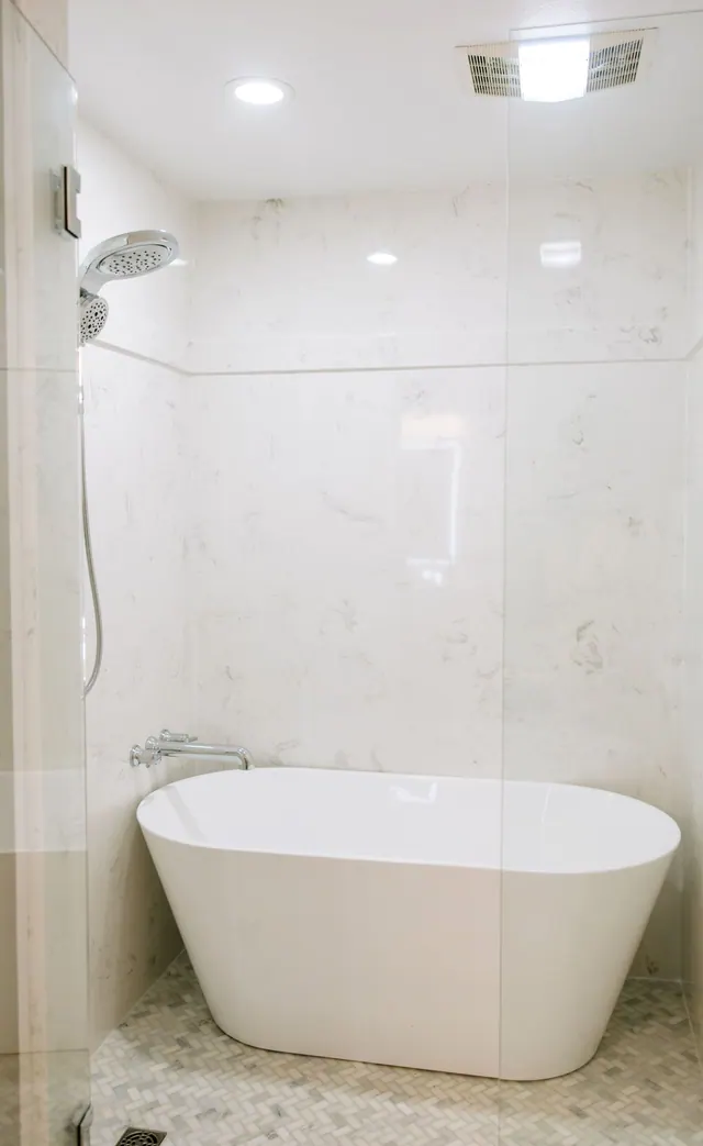 Freestanding tub against large-format marble-look wall panels