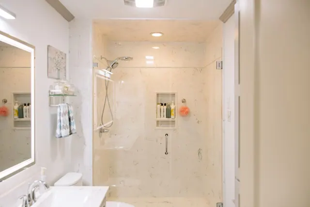 Glass shower and backlit mirror in a cream bathroom