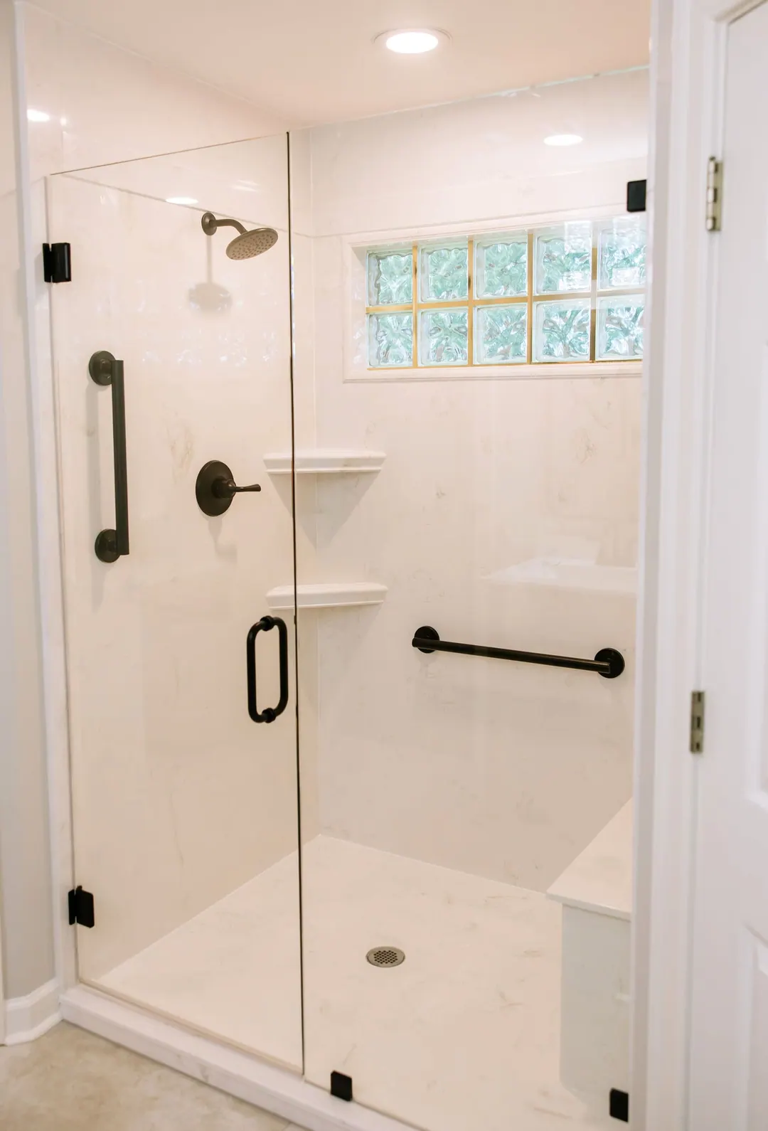 Glass-block window above a walk-in shower with matte black fixtures