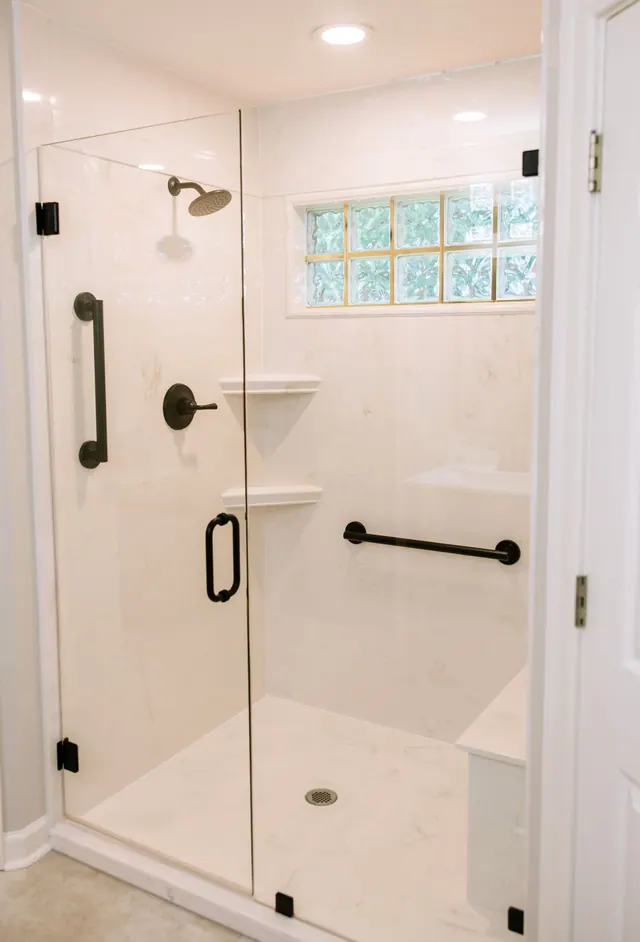 Glass-block window above a walk-in shower with matte black fixtures