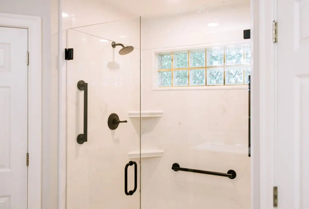 Walk-in shower with a corner shelf, handheld wand and two grab bars