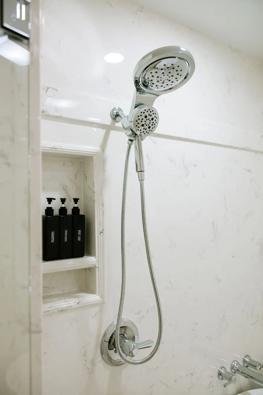Recessed shower niche beside a chrome handheld shower