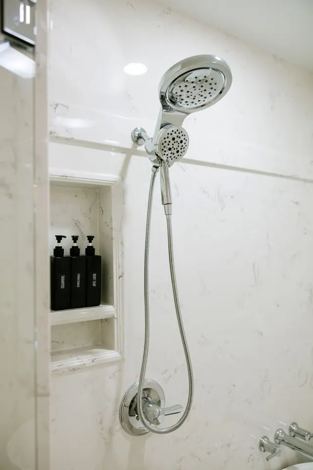 Recessed shower niche beside a chrome handheld shower