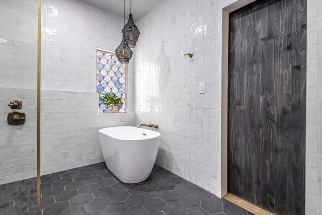 Freestanding tub beside a dark stained barn door