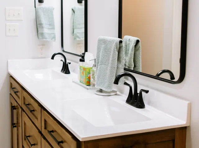 Close view of a stained vanity with an integrated white top and black faucets