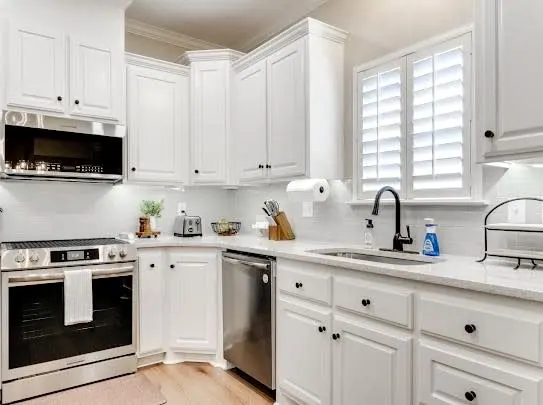 After: White painted kitchen with new counters and stainless appliances