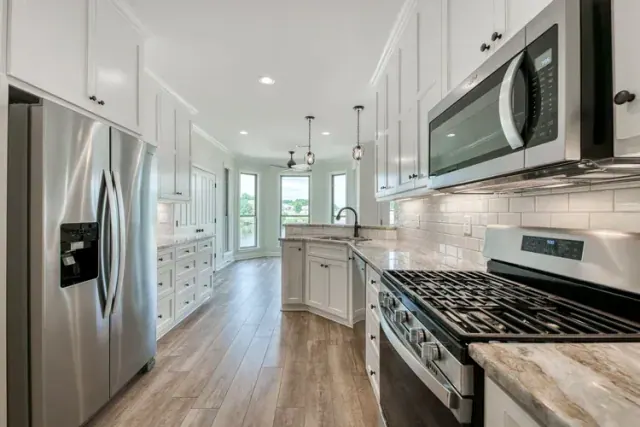 White kitchen with a gas range and wide plank wood-look floor