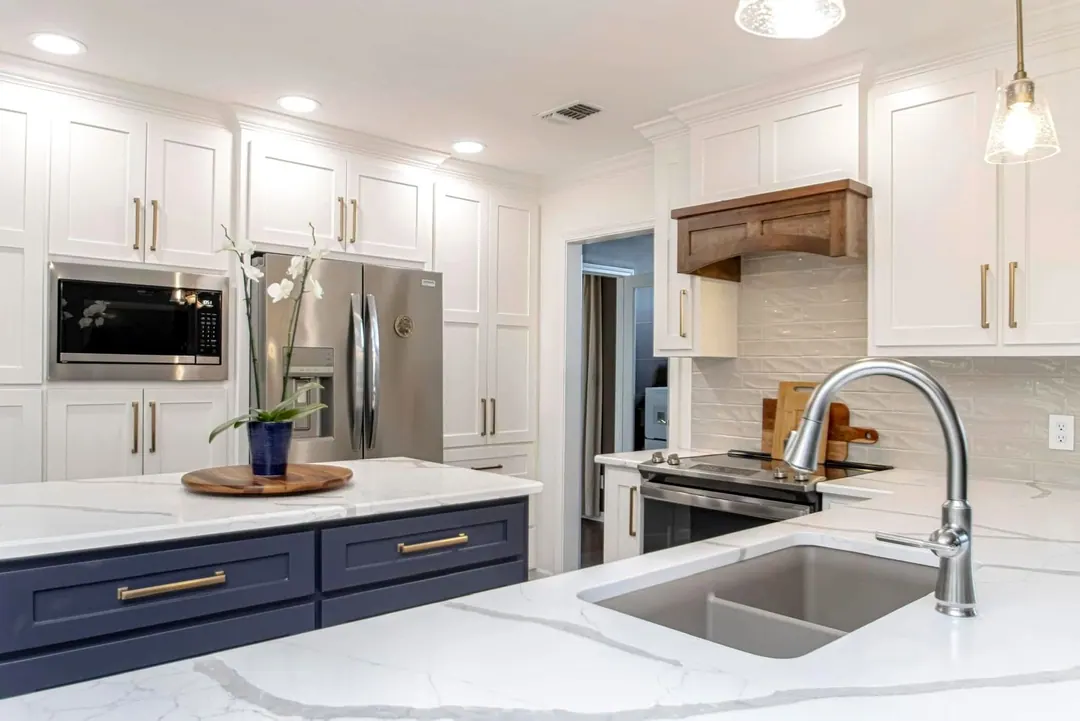 White kitchen with a navy island, quartz tops and a farmhouse sink