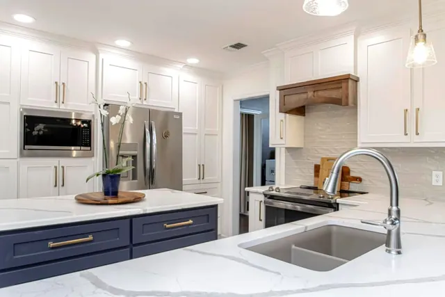 White kitchen with a navy island, quartz tops and a farmhouse sink