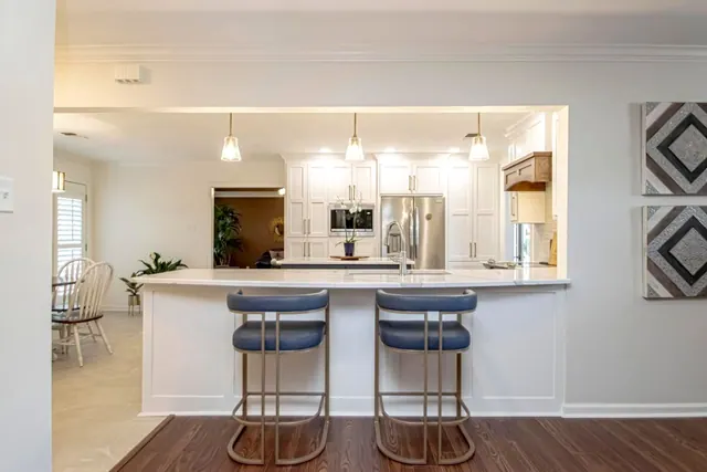 Open kitchen pass-through with a bar top and two blue stools
