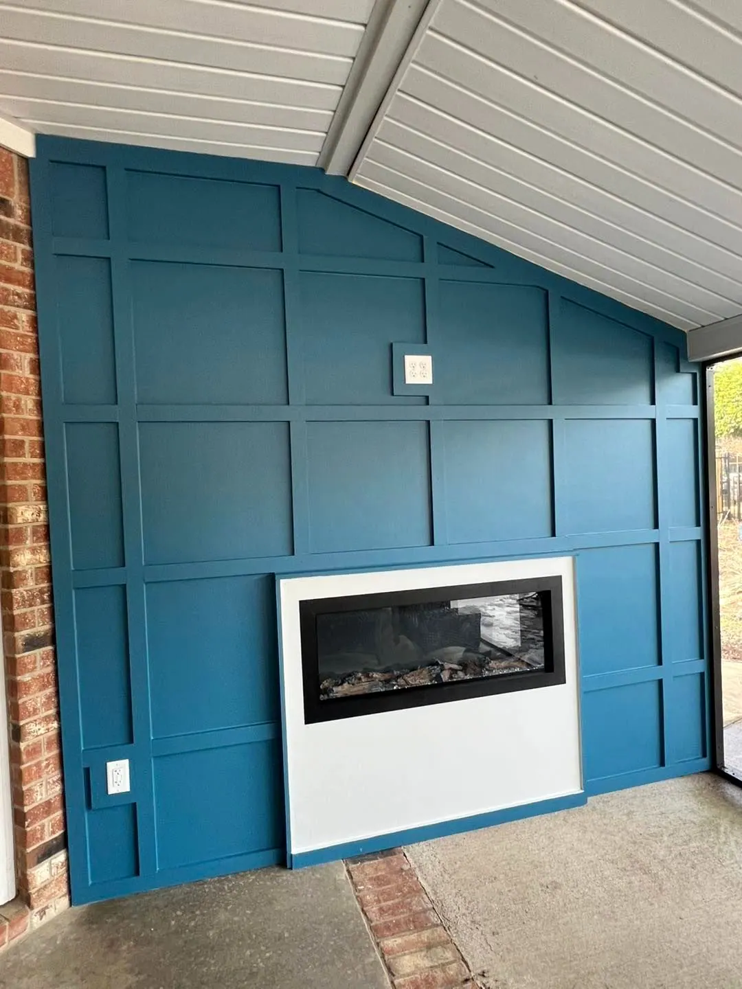 After: Blue board-and-batten wall with a modern fireplace on a covered porch