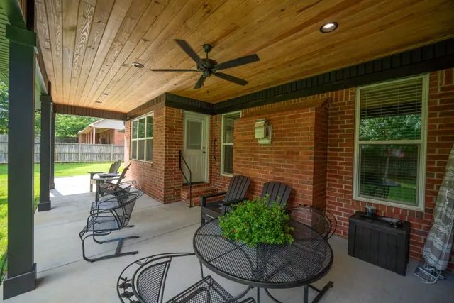 Covered brick patio with a wood ceiling, rockers and a bistro table