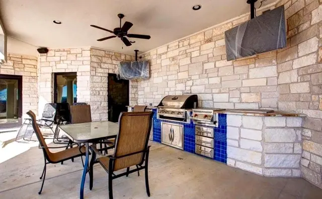 Outdoor kitchen in stacked stone with a blue tile grill surround