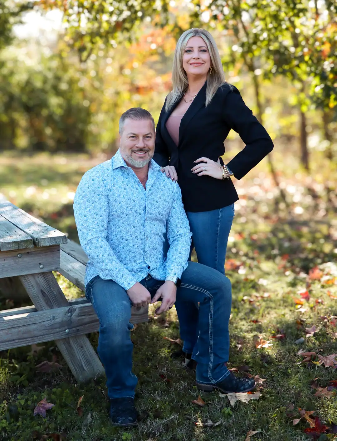 Scott and Cindy Lucas outdoors on a bench among autumn trees