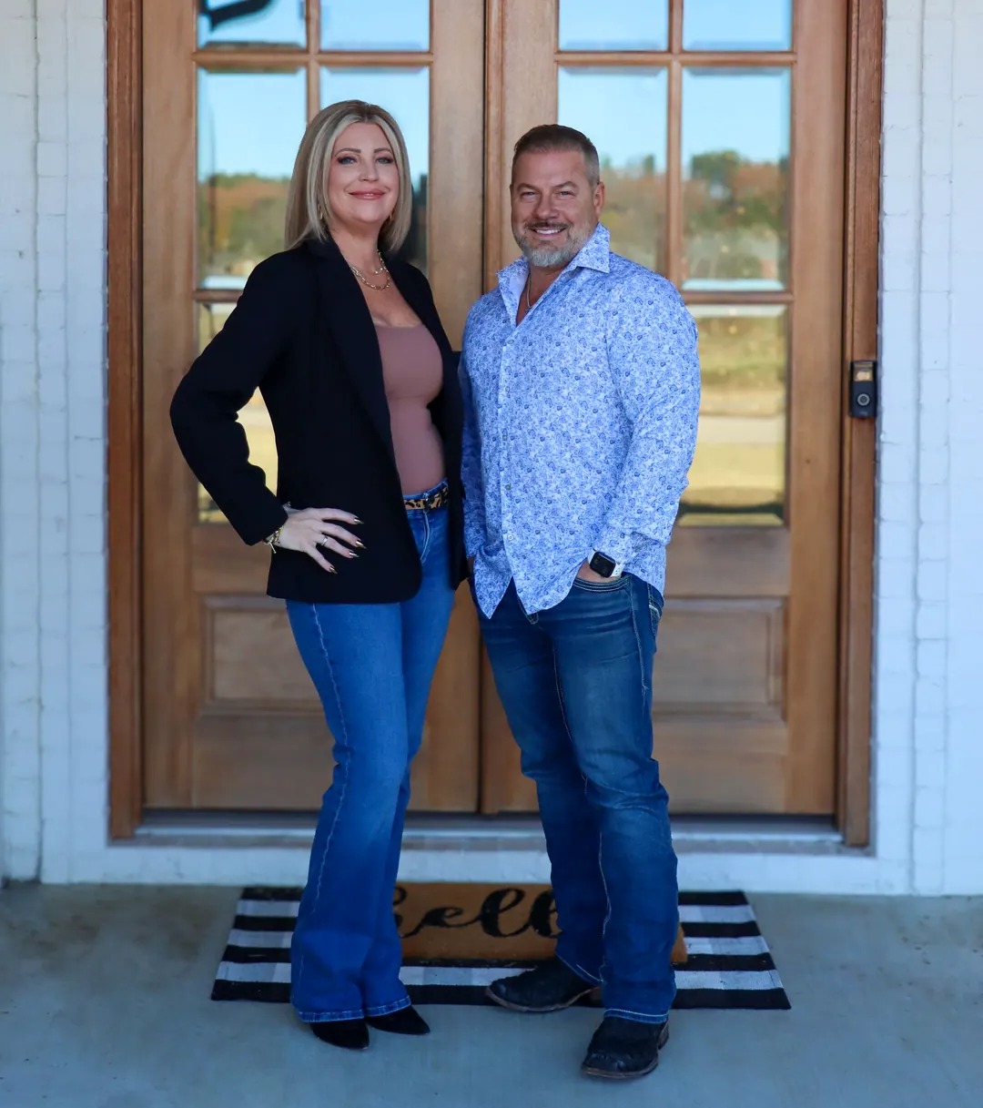Scott and Cindy Lucas standing at a wood front door